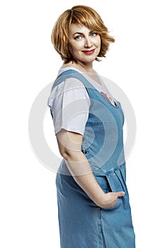 Laughing beautiful middle-aged woman with red hair in denim overalls. Isolated on a white background. Vertical
