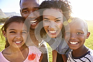 Laughing black family outdoors, close up, back lit portrait