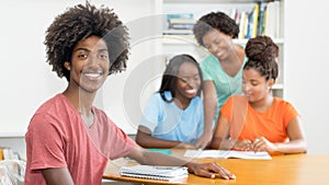 Laughing black male student at desk with group of learning african american students