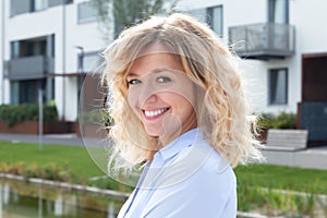 Laughing blond woman in front of her new apartment