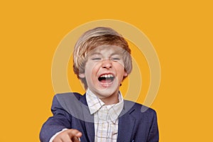 Laughing boy blond points his finger at the camera. ridicule