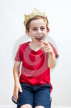 Laughing boy with crown and tooth missing pointing his finger