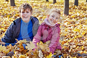 Laughing boy and girl sit on ground in drift of photo