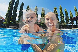 Laughing boy with joyful mother summing in the pool