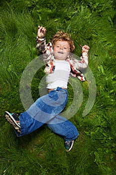 Laughing boy rolling on grass