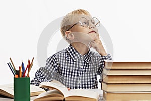 The laughing boy sits at the table and does his homework. White background