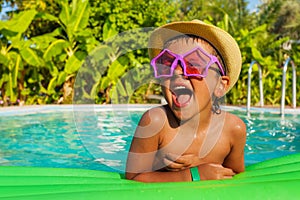 Laughing boy in star-shaped sunglasses on airbed