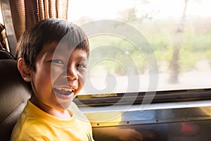 A laughing boy is traveling to the city by the metropolis bus in the morning. he enjoy with this transportation, traffic not jam