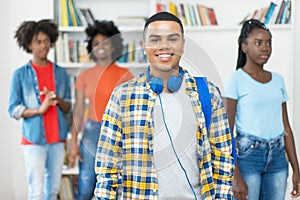 Laughing brazilian male college student with braces and group of other young adults