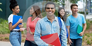 Laughing brazilian male student with braces and group of multi ethnic young adults