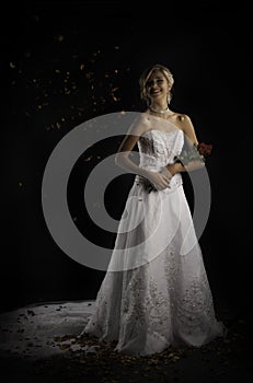 Laughing bride being thrown with rose petals while holding bouquet photo