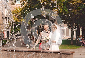 Laughing bride and groom against the background of a city fountain