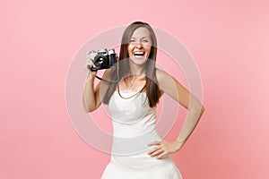 Laughing bride woman in white wedding dress holding retro vintage photo camera, choosing staff, photographer on