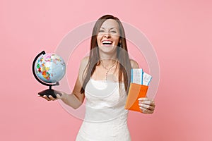 Laughing bride woman in white wedding dress holding world globe, passport boarding pass ticket going abroad for