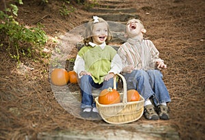 Laughing Brother and Sister Children Sitting on Wood Steps with Pumpkins