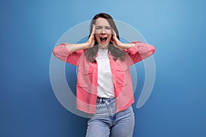 laughing brunette young woman in pink shirt and jeans on studio isolated background