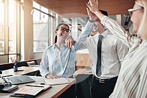Laughing businesspeople high fiving together in an office photo