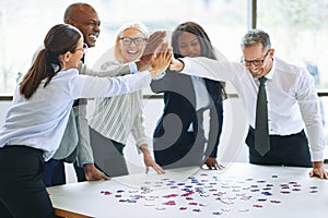 Laughing businesspeople high fiving together while solving a jig photo