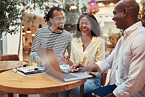 Laughing businesspeople working on a laptop in an office lounge