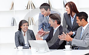 Laughing businesswoman applauded by her team