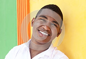 Laughing caribbean guy in front of a colorful wall