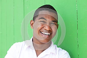 Laughing caribbean guy in front of a green wall
