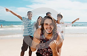 Laughing caucasian man with cheering young adults at beach