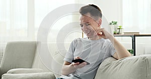 Laughing Caucasian Man Enjoying Phone Use on the Couch