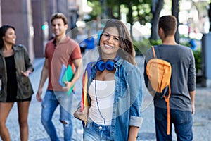Laughing caucasian young adult woman walking in city with group of students