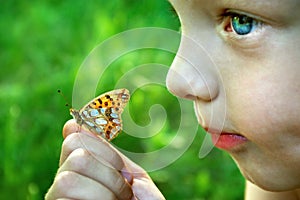 Laughing child. Butterfly sitting on the hand of a child. Child with a butterfly. Selective focus.