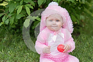 Laughing child at Easter egg hunt baby in pink bunny costume