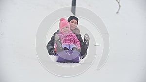 Laughing child with mother sledding in snow