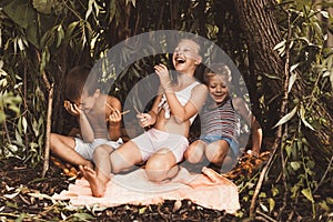 Laughing children play in a hut made of twigs and leaves. Wooden house in the village