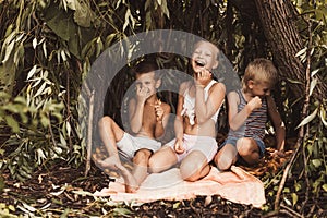 Laughing children play in a hut made of twigs and leaves. Wooden house in the village