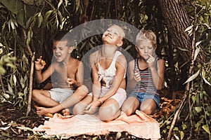 Laughing children play in a hut made of twigs and leaves. Wooden house in the village