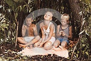 Laughing children play in a hut made of twigs and leaves. Wooden house in the village