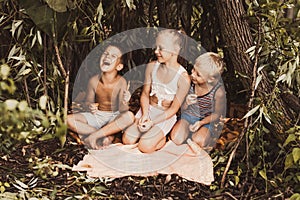 Laughing children play in a hut made of twigs and leaves. Wooden house in the village