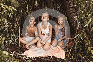 Laughing children play in a hut made of twigs and leaves. Wooden house in the village