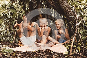 Laughing children play in a hut made of twigs and leaves. Wooden house in the village