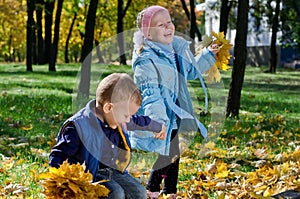 Laughing children playing with fall leaves