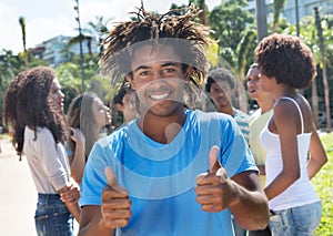 Laughing colombian guy showing thumbs with friends