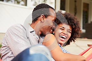 Laughing couple cuddling in a hammock