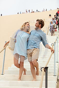 laughing couple descending steps sand dune
