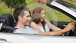 Laughing couple driving in a silver convertible