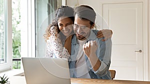 Laughing couple embracing by computer winning at sports betting