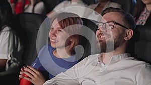 Laughing couple enjoying comedy in cinema.