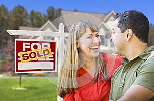 Laughing Couple in Front of Sold Real Estate Sign and House