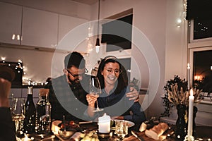 Laughing couple having fun at a dinner party with friends