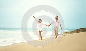 Laughing couple in love holding hand on beach