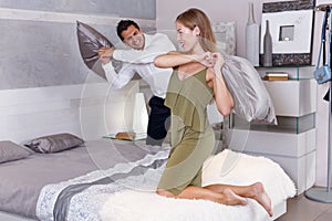 Laughing couple during pillow fight on bed